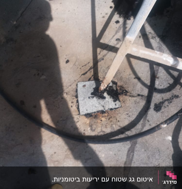 A metal pole sealed to a concrete surface with black sealant.